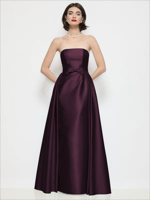 Plum strapless satin column dress with waist bow detail and full gathered skirt