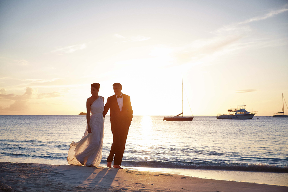 couple walking along beach in setset